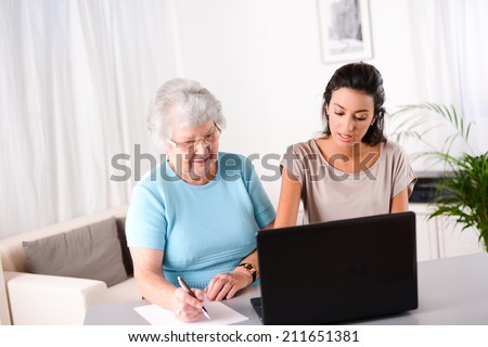 cheerful young woman helping an elderly person using laptop  computer for internet search and email