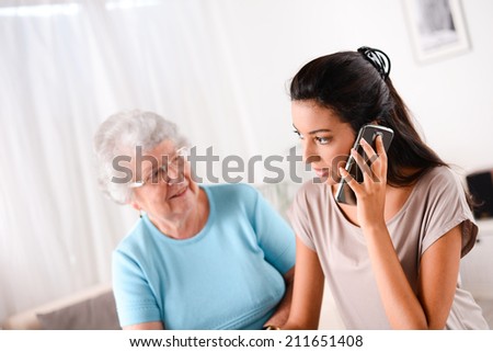 cheerful young woman helping an old person doing paperwork and telephone call
