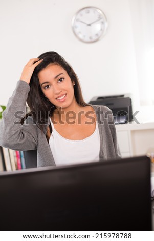 cheerful young woman office worker siting at desk and working with a laptop computer