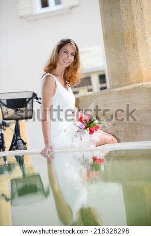 attractive and romantic young woman playing with water in public wash-house during a summer vacation bike ride