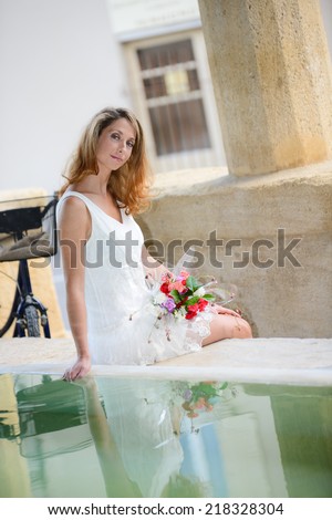 attractive and romantic young woman playing with water in public wash-house during a summer vacation bike ride