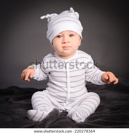 isolated studio portrait on grey background of lovely toddler baby boy playing and laughing