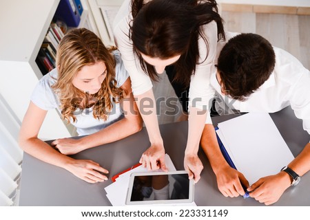 beautiful young woman private teacher helping two students doing their homework