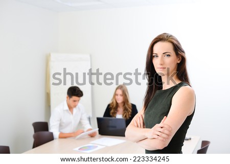 Beautiful young woman executive manager in a meeting room isolated with business team in background