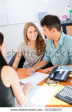 happy young couple getting advice in office with beautiful business woman