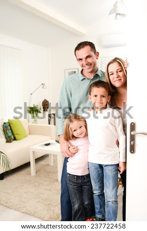 happy family with young kids welcoming a guests at their house door wide open.