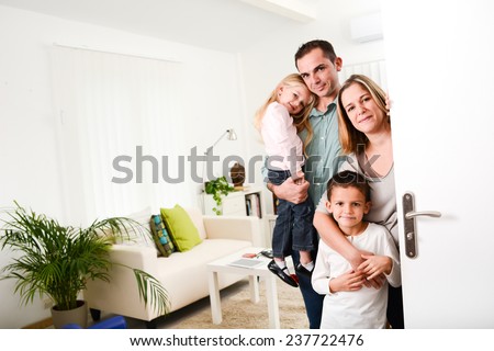 happy family with young kids welcoming a guests at their house door wide open.