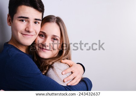 studio portrait of a beautiful young couple man and woman love standing against blue gray background