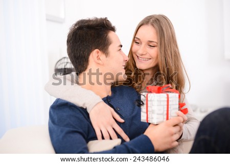 cheerful young couple man and woman at home offering to each other gifts for lover\'s valentine day