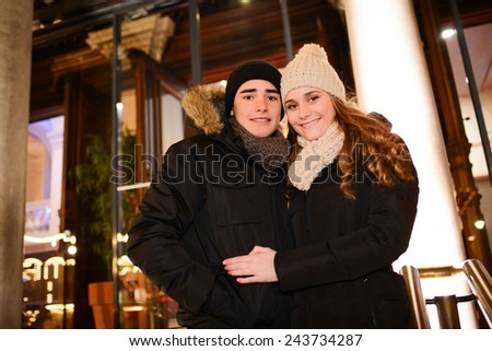 cheerful happy young couple having fun downtown at night during winter
