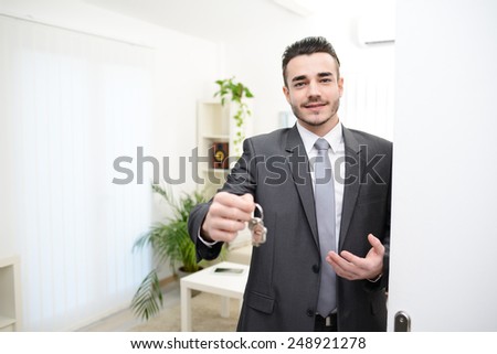 young realtor handing house keys in doorway of new house