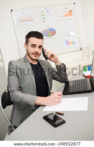 young man in office working with laptop computer and phone