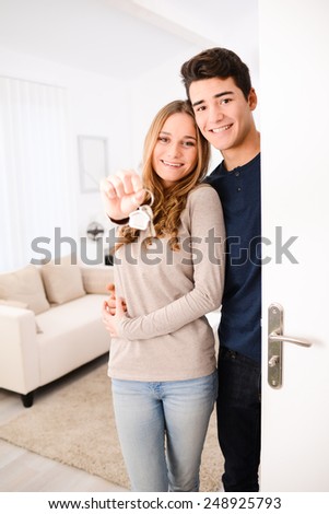 happy young couple welcome in  new house showing the door keys at entrance door