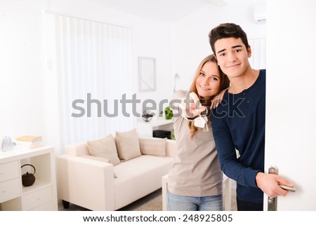 happy young couple welcome in  new house showing the door keys at entrance door