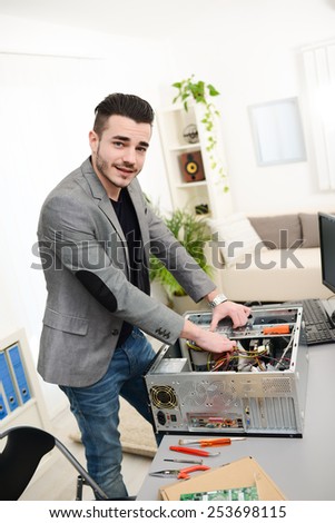 handsome young man computer repair fixing a desktop computer at customers house