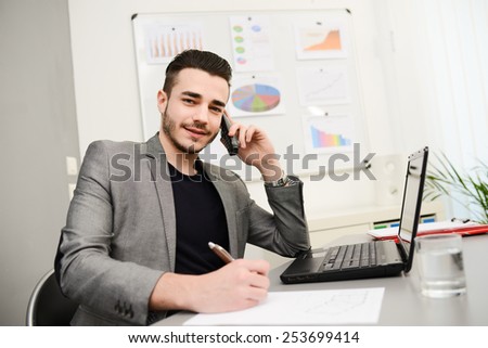 young man in office working with laptop computer and phone