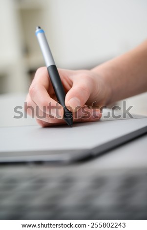 close up detail of hands working with graphic tablet and a desktop keyboard