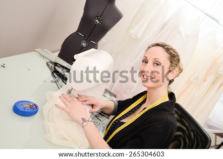 cheerful young seamstress sewing a wedding dress on her sewing machine