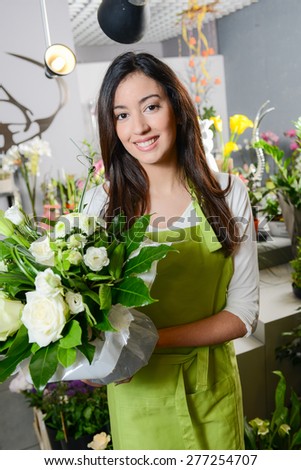 cheerful young woman brunette florist selling flowers in a flower shop