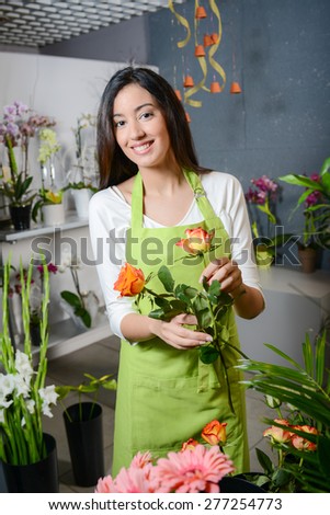 cheerful young woman brunette florist selling flowers in a flower shop