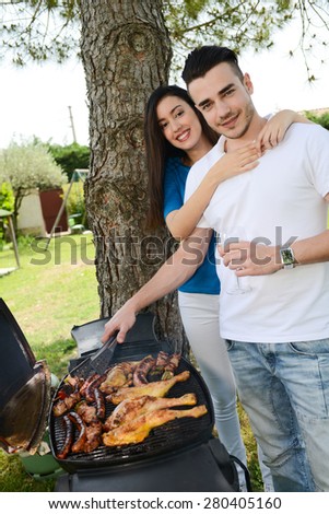cheerful young couple cooking barbecue outdoor in summer garden party