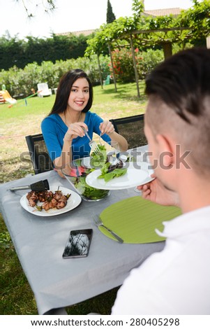 cheerful young couple man and woman having lunch outdoor in a summer barbecue garden party