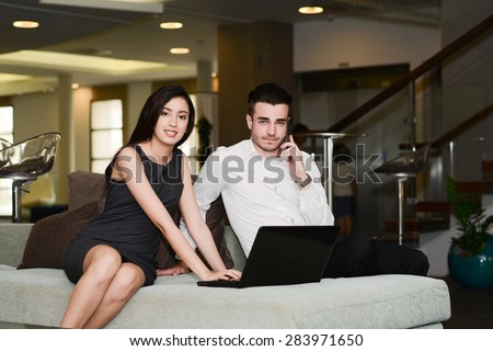 two business people man and woman working on a computer while waiting in airport lounge