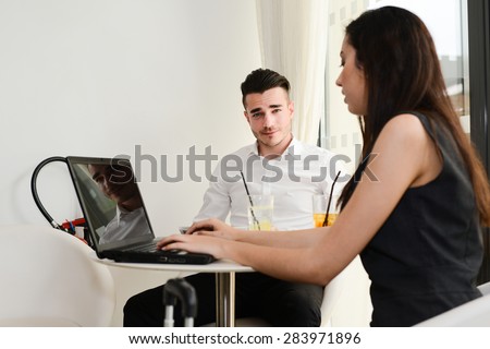 two business people man and woman working on computer while waiting in an airport lounge