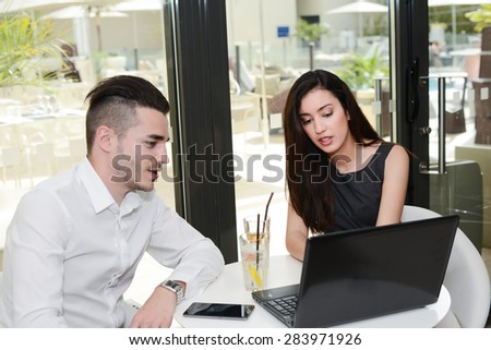 two business people man and woman working on computer while waiting in an airport lounge