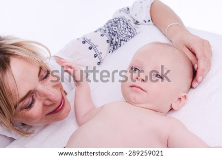 mature blonde woman playing and taking care of her lovely new born baby boy