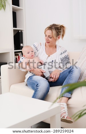 young woman at home playing and taking care of lovely new born baby boy