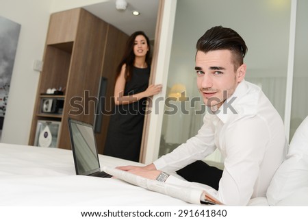 handsome young business man working on computer with woman in  hotel room