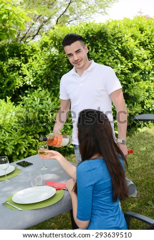 cheerful young couple man and woman cheering with a glass of wine outdoor in a summer barbecue garden party
