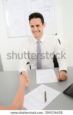 handsome young business man handshake with customer in office after signing agreement sales contract