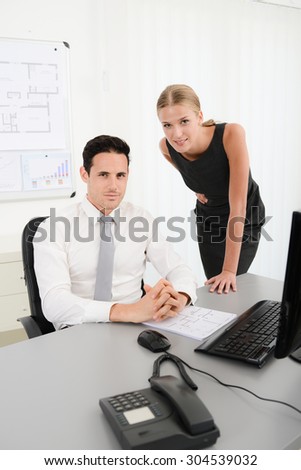 two young business people in office meeting and looking at data in computer