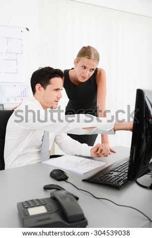 two young business people in office meeting and looking at data in computer