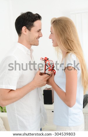beautiful and cheerful young couple in love offering gift to each other for valentine day or birthday