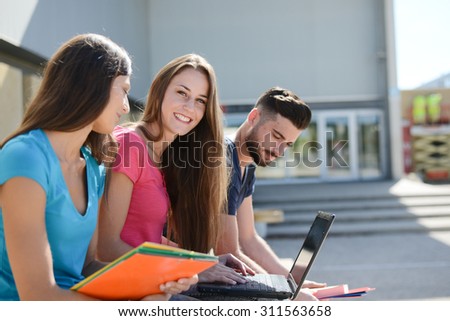 portrait of an attractive cheerful young student woman outdoor in front of high school campus