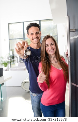 happy young couple at their new house front door proud to show home keys