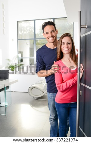 happy young couple at new house front door welcoming people