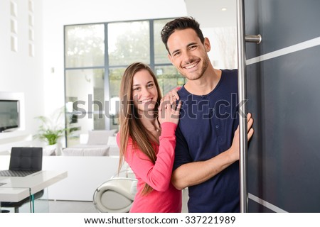 happy young couple at new house front door welcoming people