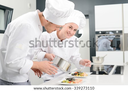student and teacher in a professional cook school kitchen preparing a plate for restaurant