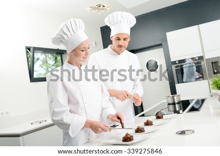 student and teacher in a professional cook school kitchen preparing a chocolate dessert