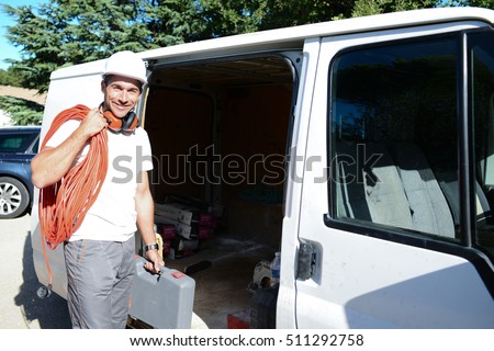young electrician artisan taking tools out of his professional truck van