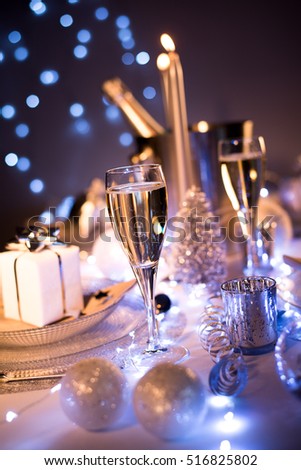 dim light white silver and blue romantic new year eve or christmas table in a luxury restaurant with champagne