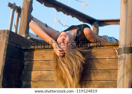 Joyful girl lying on the deck of an old wooden ship