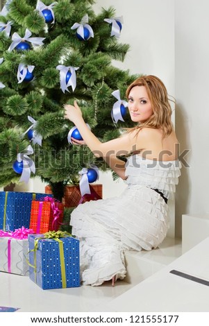 Young woman sits near a Christmas tree