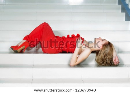 Young woman in a red pantsuit lying on the stairs
