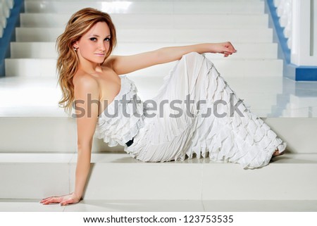 Attractive young woman in a white dress lying on the stairs