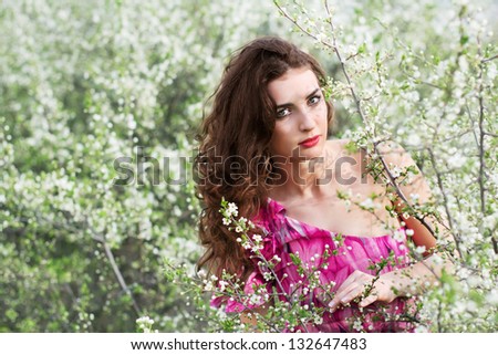 Beautiful brunette wearing pink dress posing in flowering trees